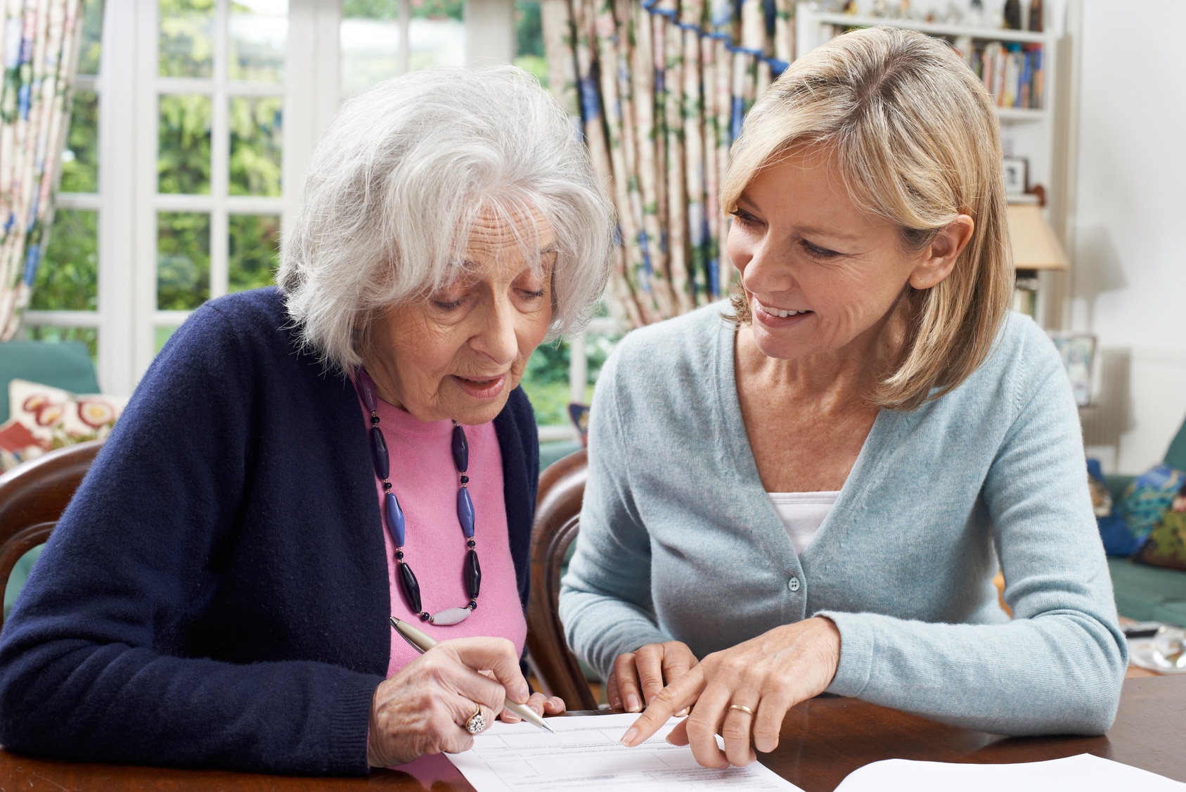 Junge Frau hilft Seniorin ein Formular auszufüllen