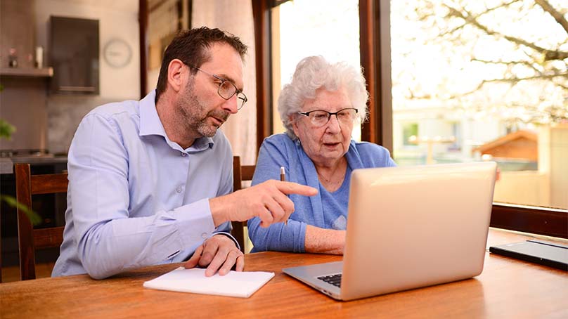 ein Digital Coach unterstützt eine Seniorin beim Einrichten Ihres neuen Laptops